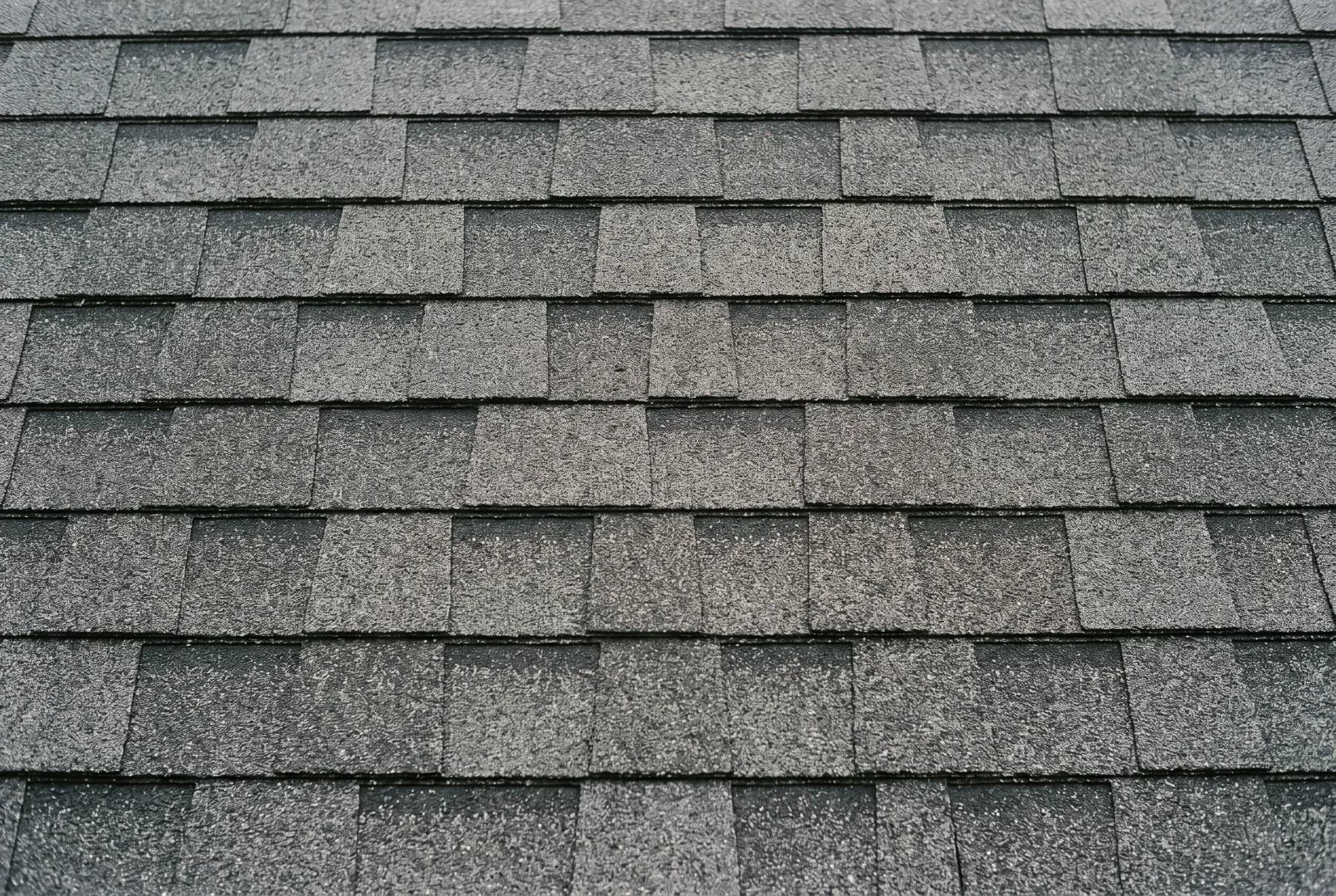 A close view of a newly laid charcoal architectural asphalt shingle roof surface.